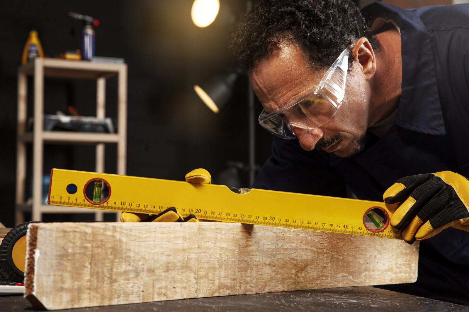 A carpenter sighting down a spirit level laid along a length of timber, checking it is true
