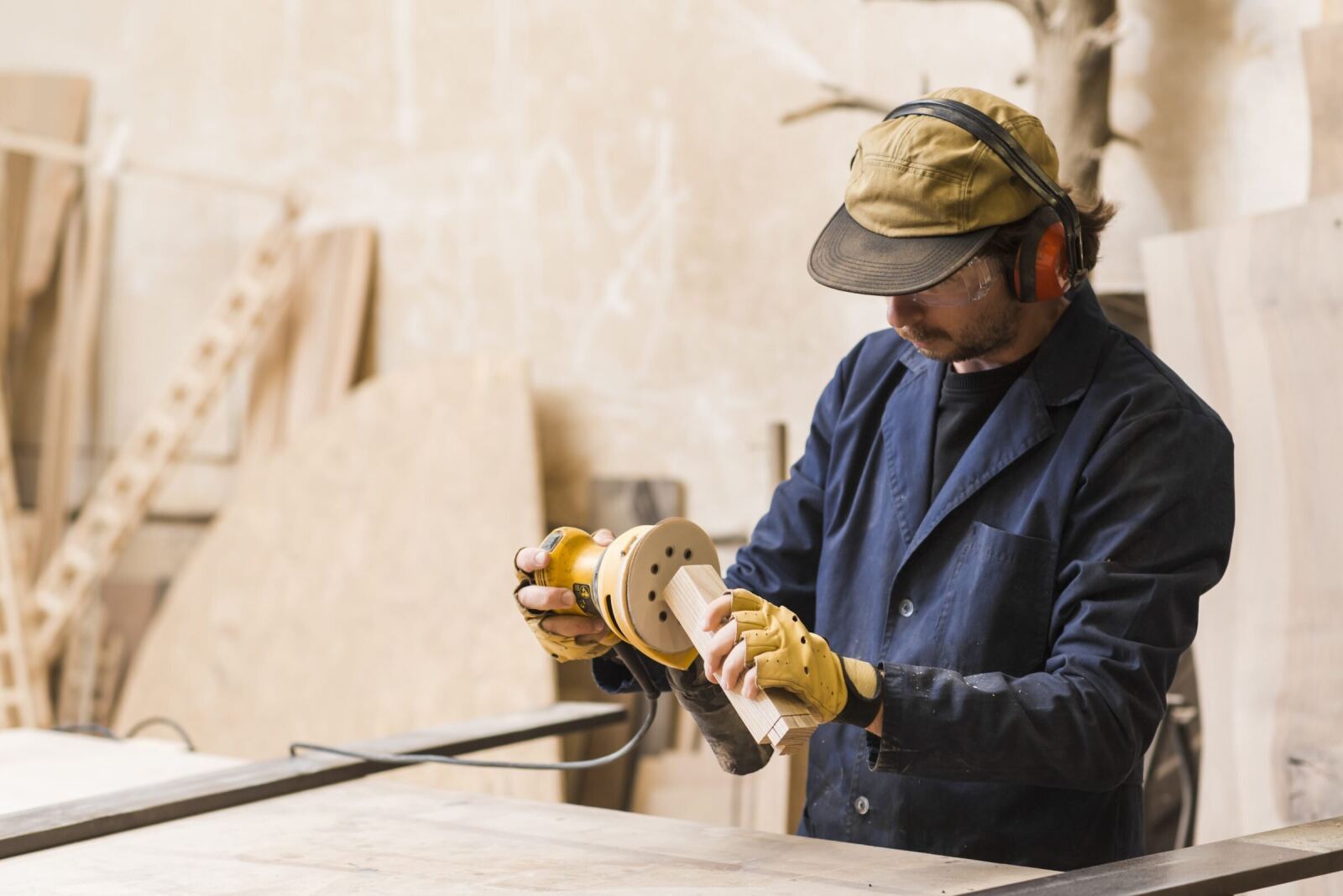 A carpenter running an orbital sander over a block of timber in the workshop