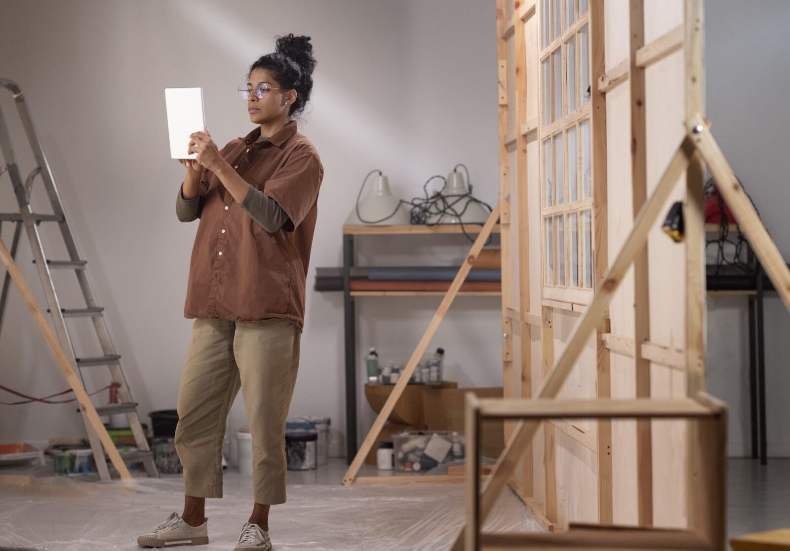 A carpenter standing back from a timber-framed window wall, photographing it on a tablet