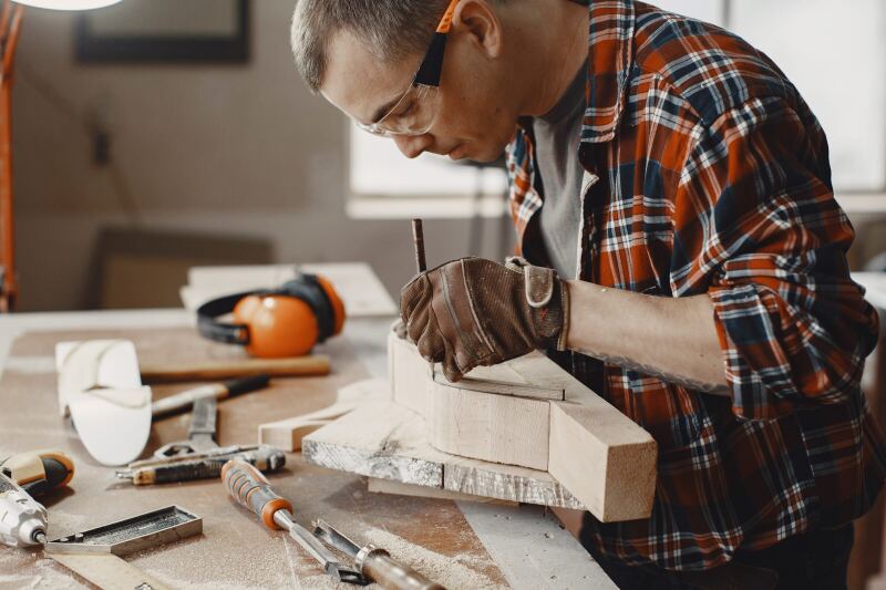 A carpenter cutting a joint into a structural timber at the bench